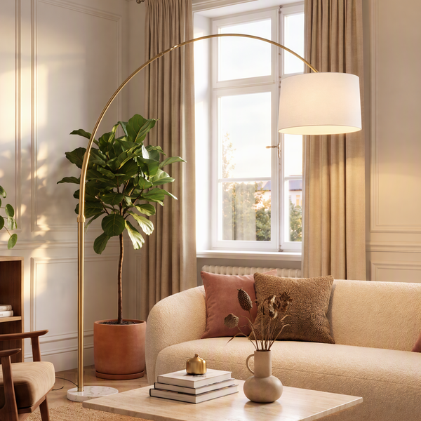Moderne Bogenlampe mit Metallgestell und Lampenschirm in einem stilvoll eingerichteten Wohnzimmer mit Sofa und Zimmerpflanze.
