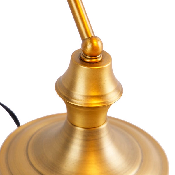 Detailaufnahme einer goldenen Lampe, die auf einem Tisch oder Schreibtisch platziert wird.