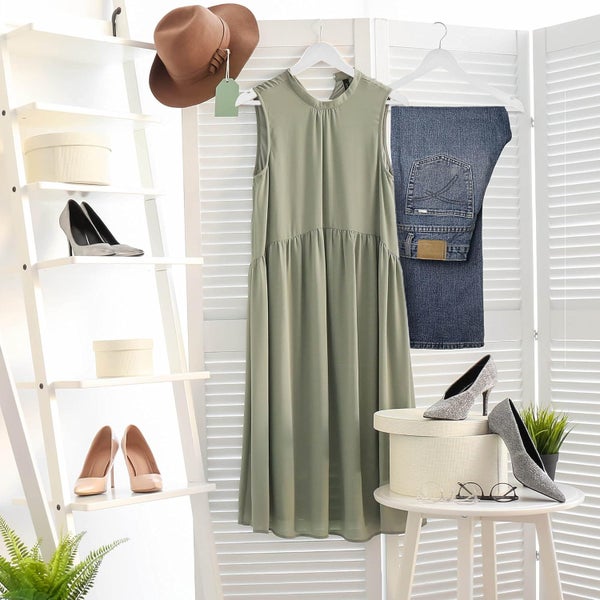 Szene mit Kleiderständer, Kleid, Hose, Schuhen, Hut, Schachteln und Dekoration