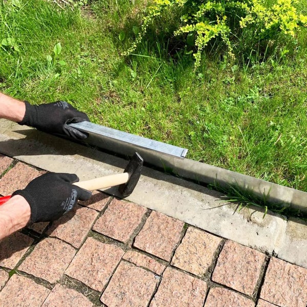 Mann befestigt Rasenkante mit Hammer