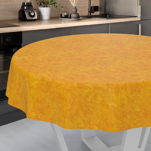 Rundes, oranges Tischtuch mit marmorierter Struktur auf einem Tischfuß in einer modernen, aufgeräumten Küche.