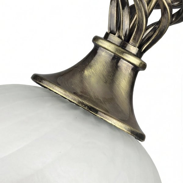 Detailaufnahme einer Deckenleuchte mit einem Lampenschirm aus Glas und einer bronzefarbenen Halterung.