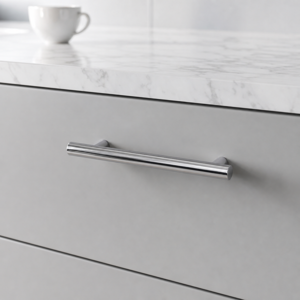 Moderner Relinggriff aus Metall in Chrom-Optik an einer grauen Schublade unter einer Arbeitsplatte in Marmor-Optik.