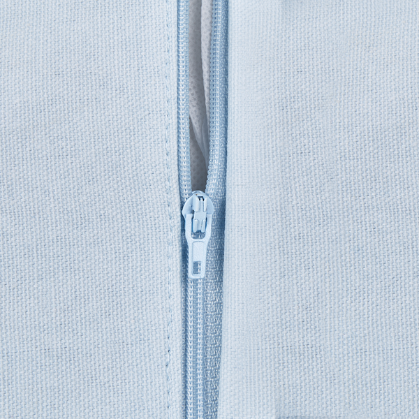 Detailansicht eines Reißverschlusses an einem hellblauen Kissenbezug aus gewebtem Stoff.
