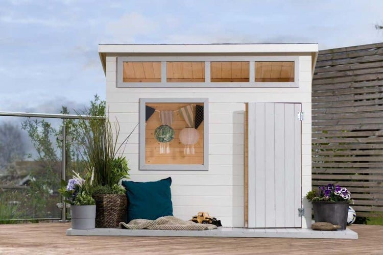 Modernes weißes Spielhaus aus Holz mit Pultdach, quadratischem Fenster und Einzeltür auf einer hellen Holzterrasse im Garten.