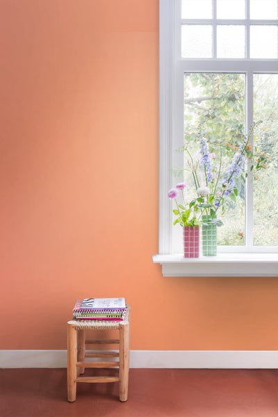 Raumansicht mit einem Hocker, Büchern, Blumen und einer Fensterbank