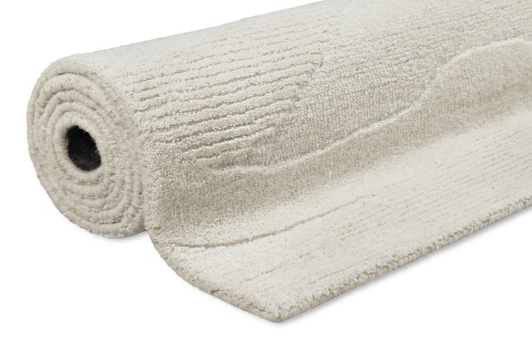 Aufgerollter cremefarbener Teppich mit strukturierter Oberfläche aus weichem Material.