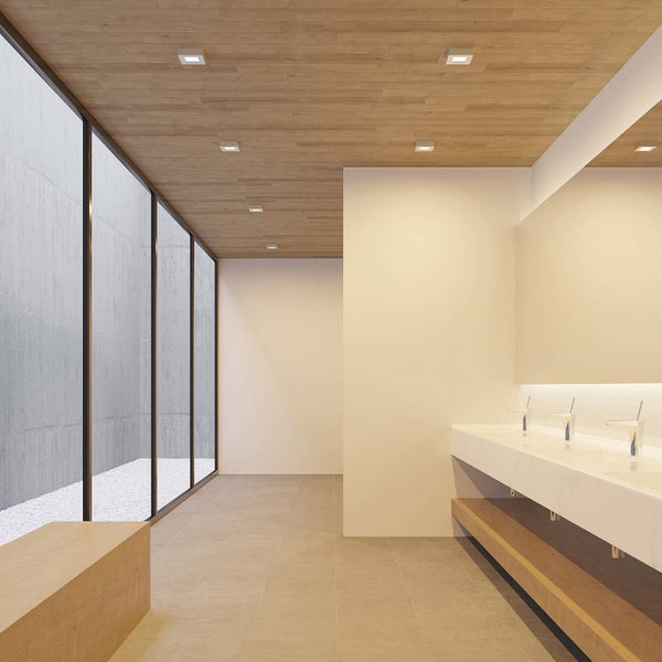 Modernes minimalistisches Badezimmer mit Holzdecke, Einbauleuchten, grossen Fenstern, Waschtisch mit mehreren Armaturen und grossem Spiegel.