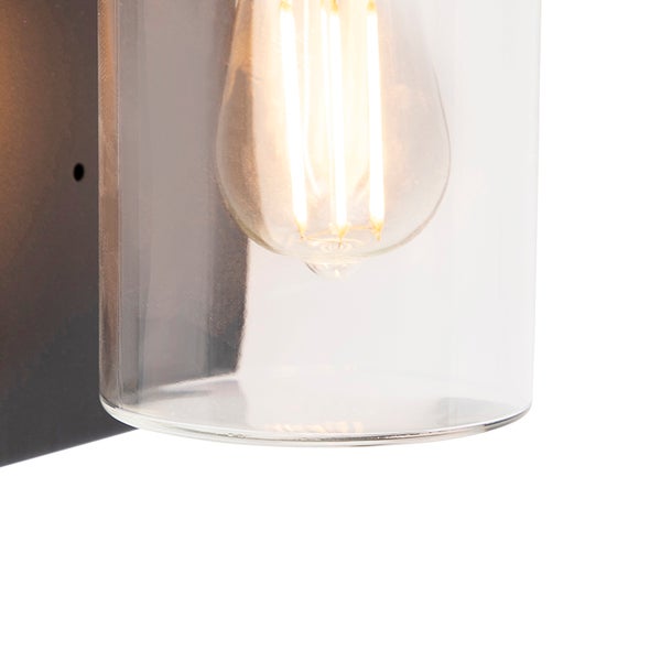 Detailaufnahme einer Wandlampe mit Glaszylinder und leuchtendem Filament-Leuchtmittel.