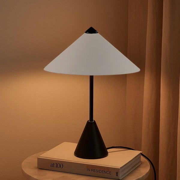 Dekorative Tischleuchte mit Kegelfuß und Lampenschirm auf einem Buch