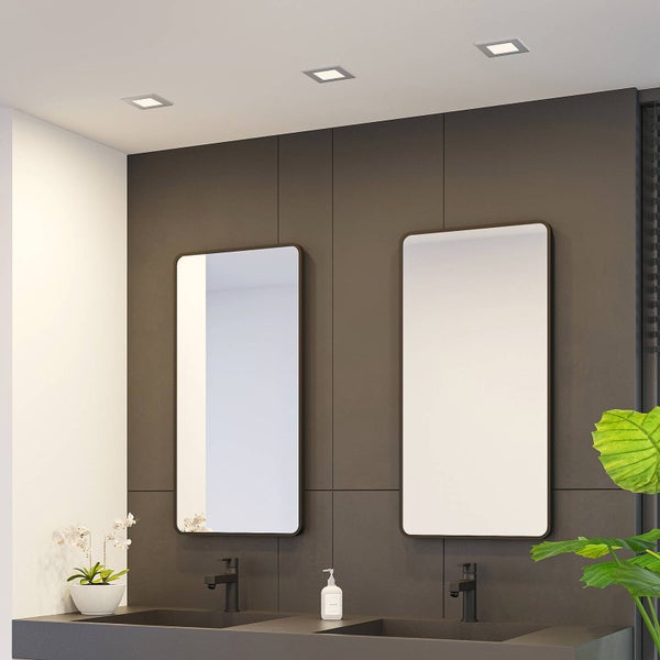 Modernes Badezimmer mit zwei rechteckigen Spiegeln, schwarzen Armaturen und quadratischen Deckeneinbauleuchten an einer dunkelgrauen Wand.