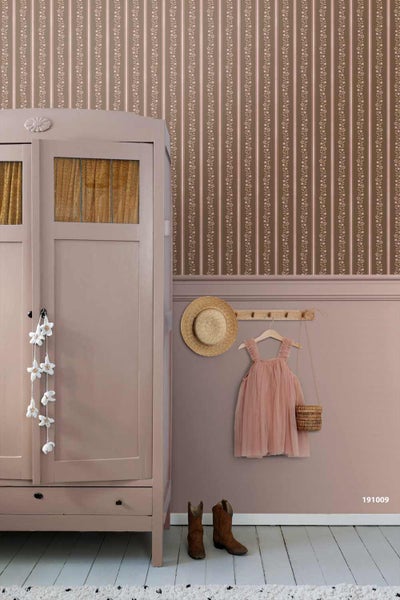 Nostalgisches Zimmer mit gestreifter Blumentapete, passender Wandfarbe, einem Holzschrank und einer Hakenleiste mit Kleidung und Strohhut.