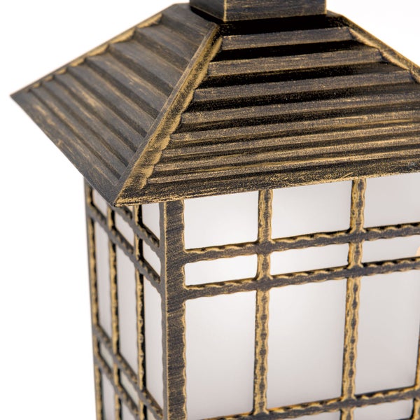 Nahaufnahme einer Außenleuchte mit goldfarbenem Antik-Finish, Gitter-Design und weißem Diffusor.