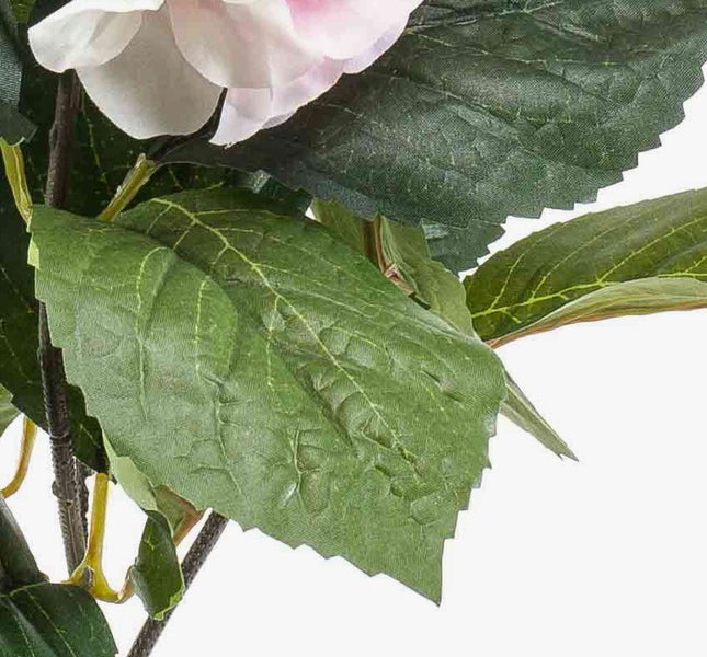 Nahaufnahme einer künstlichen Pflanze mit grünen Blättern und einer rosa Blüte, Fokus auf die Blattstruktur.