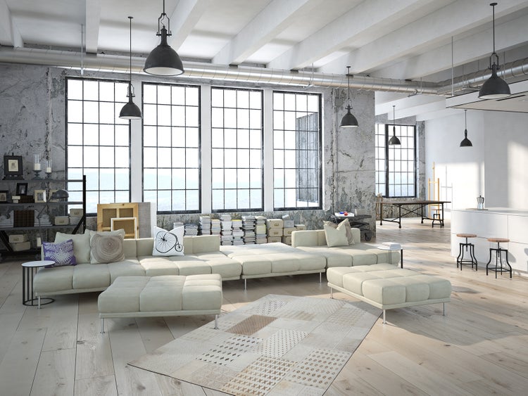 Großzügiges Loft Wohnzimmer mit industriellem Design, hellen Sofas, Parkettboden, großen Fensterfronten und dekorativen Pendelleuchten.