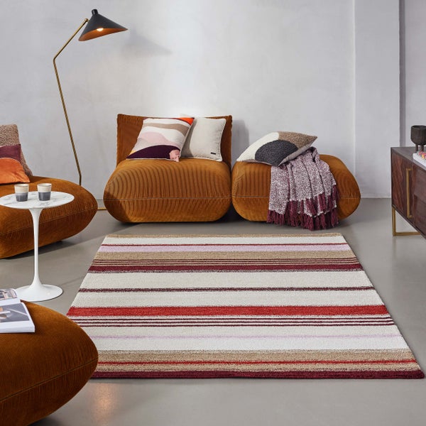 Gestreifter Teppich in einem modern eingerichteten Wohnzimmer mit braunen Cord-Sitzmöbeln und einer Stehlampe.