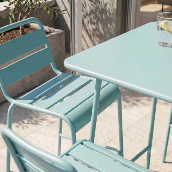 Moderne blaue Gartenmöbel aus Metall bestehend aus Tisch und Stühlen mit Latten-Design auf einer hellen Terrasse.