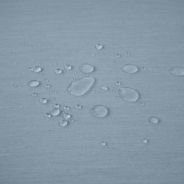 Wassertropfen perlen auf einer wasserabweisenden Stoffoberfläche ab.
