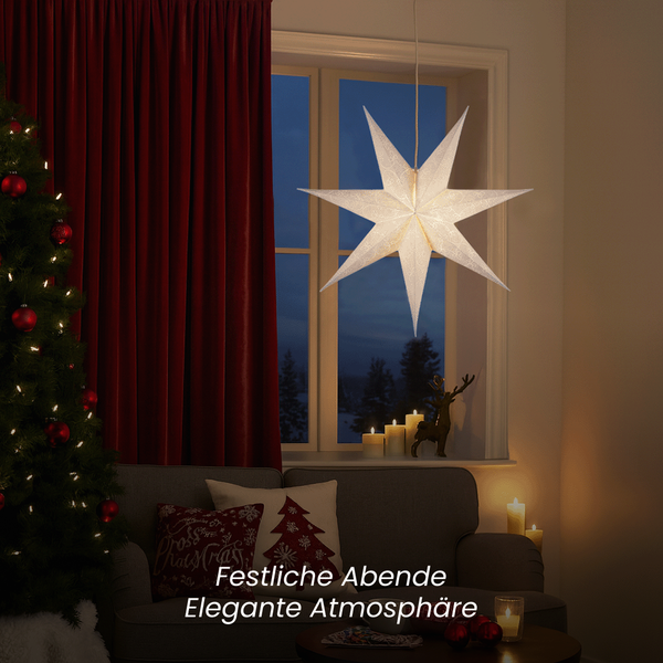 Festliche Dekoration mit einem beleuchteten Papierstern, Weihnachtbaum und roten Vorhängen für eine gemütliche Atmosphäre