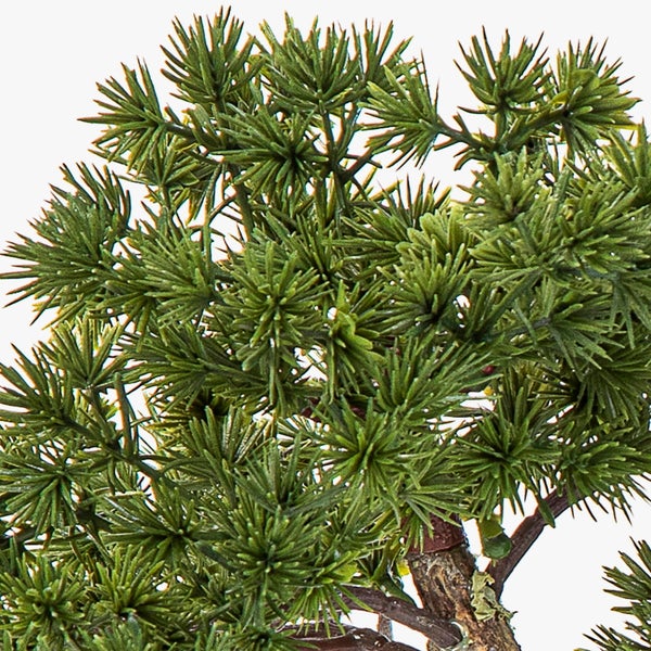 Künstliche Pflanze mit grünen Nadeln und braunem Ast, Detailansicht eines Nadelbaums für die Dekoration.