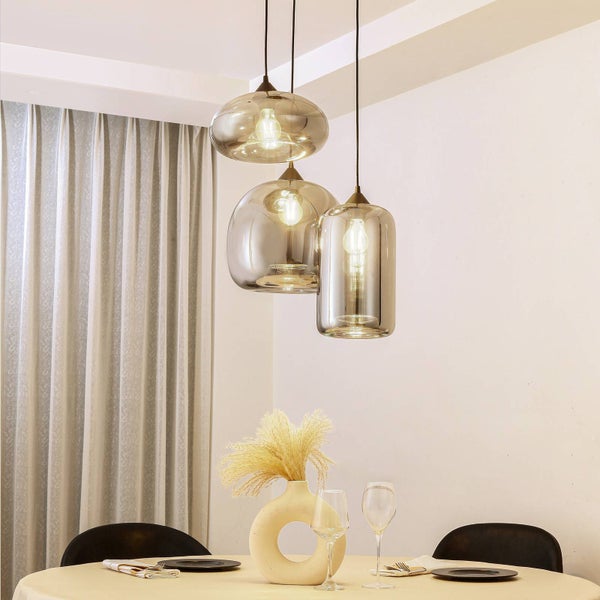 Dreiflammige Pendelleuchte mit verschieden geformten Glasschirmen über einem gedeckten Esstisch im hellen Esszimmer.