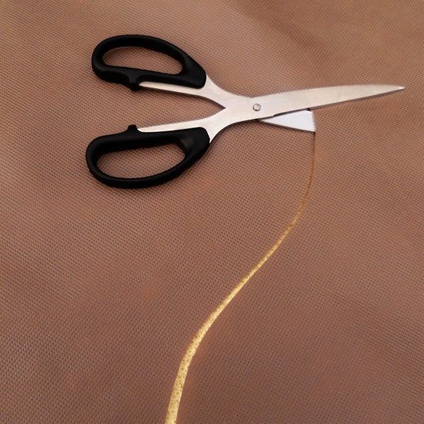 Eine Schere schneidet in ein Textil.