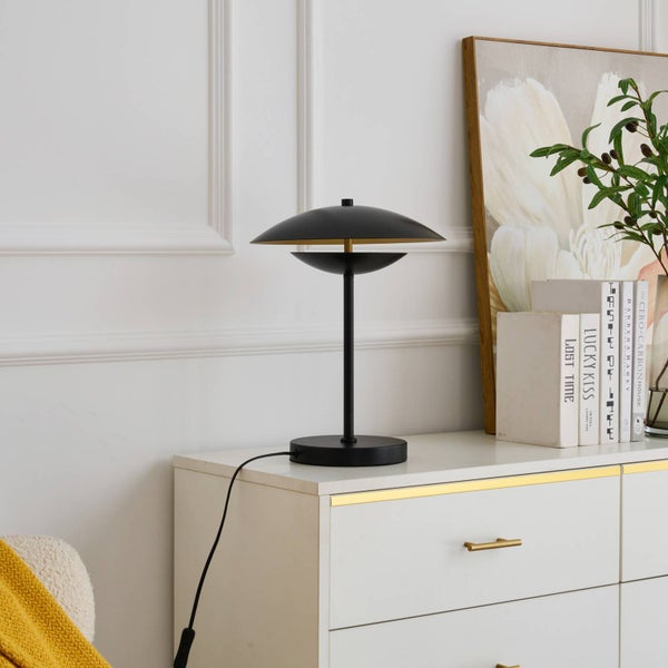 Schwarze Metall-Tischleuchte im modernen Design auf einem weißen Sideboard in einer hellen Wohnumgebung.