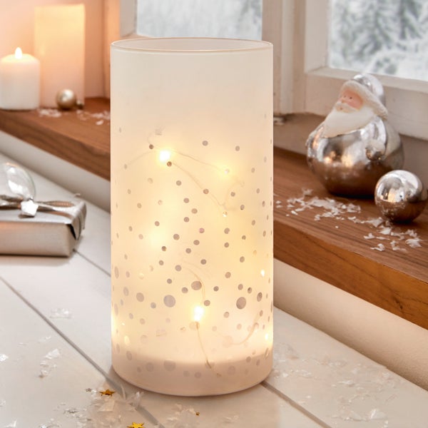 Dekorative Glaslaterne mit Punktmuster und Lichterkette als weihnachtliche Tischdekoration.