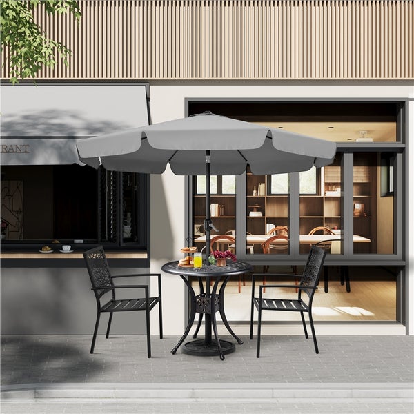 Gartensitzgruppe mit Tisch, zwei Stühlen und einem Sonnenschirm vor einem Gebäude