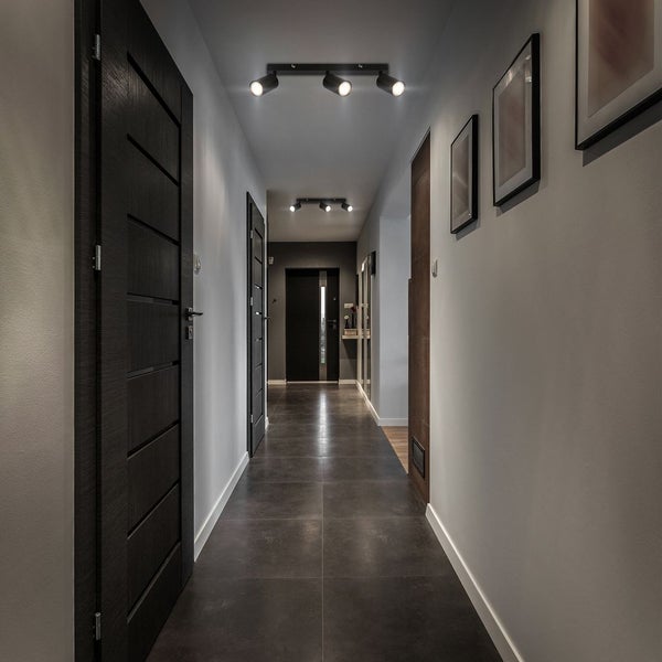 Moderner Flur mit dunklen Türen, grauen Bodenfliesen und schwarzen 3-flammigen Deckenstrahlern.