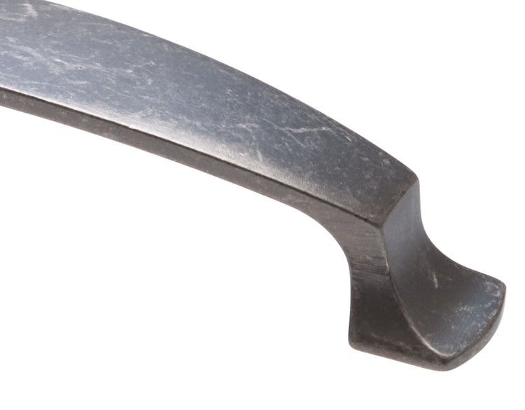Ein gebogener Möbelgriff aus Metall mit antik wirkender Oberfläche.