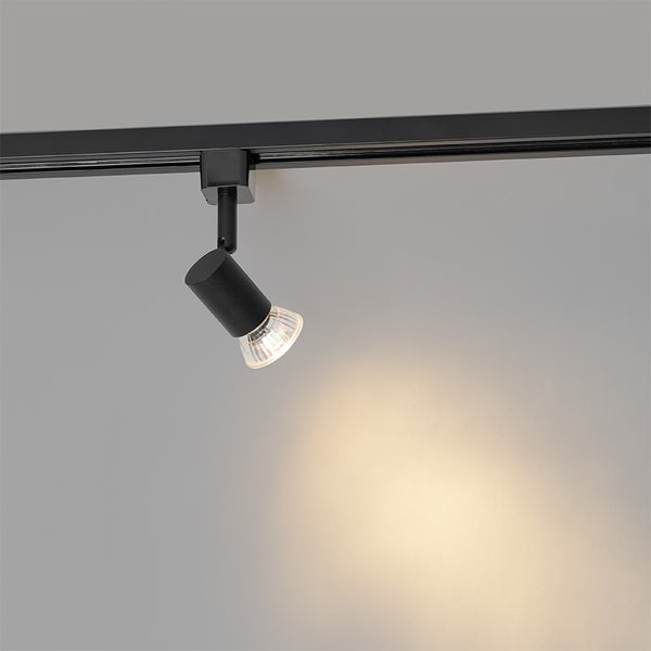 Schwarzer Schienenstrahler an einer Schiene montiert, der ein gerichtetes Licht auf eine Fläche wirft.