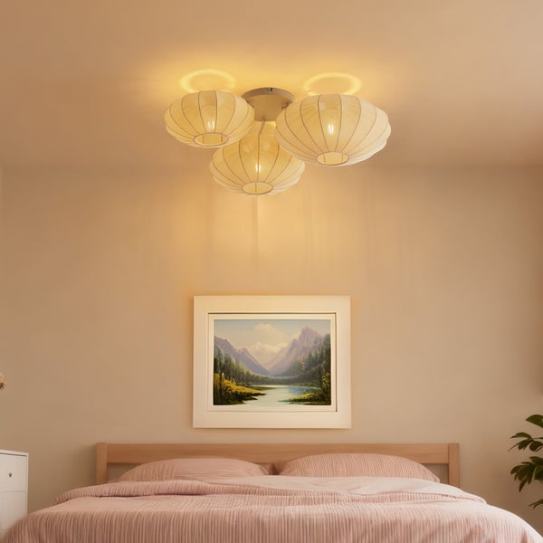 Deckenleuchte mit drei runden Textilschirmen in einem Schlafzimmer mit Doppelbett und Wandbild.