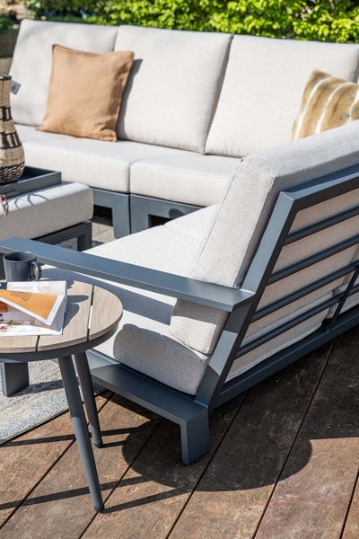 Modernes Garten-Lounge-Set aus Aluminium mit hellen Polstern auf einer Holzterrasse, inklusive Beistelltisch in Holzoptik, hell und organisiert.