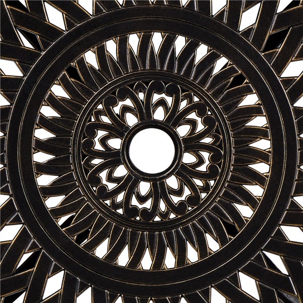 Nahaufnahme einer Tischplatte aus Gussaluminium mit ornamentalem Muster und mittigem Loch für einen Sonnenschirm.