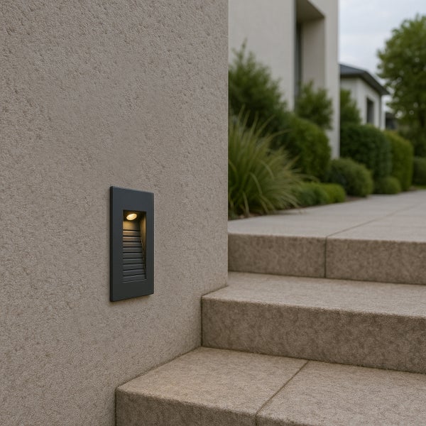 Rechteckige Wandeinbauleuchte für den Außenbereich, an einer Steinwand neben einer Außentreppe montiert, strahlt warmes Licht aus.