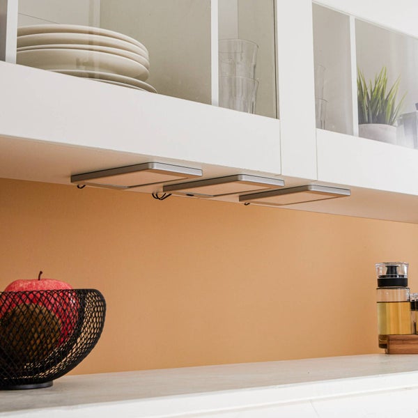 Flache LED-Unterbauleuchten unter einem weißen Küchenschrank montiert, zur Beleuchtung der Arbeitsplatte in einer hellen, organisierten Küche.