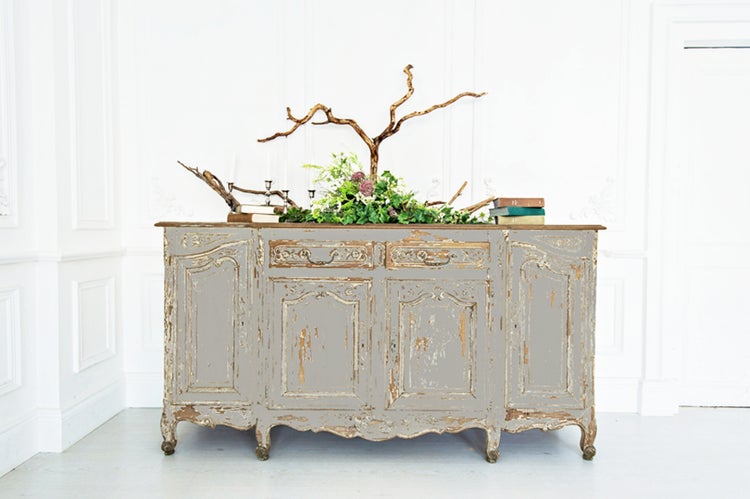 Antiker grauer Holzschrank mit floralen Dekorationen, Kerzenständern und Büchern