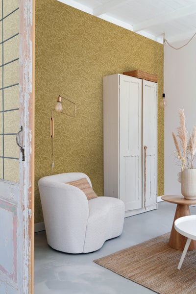 Wohnzimmer mit floral gemusterter Tapete, Sessel und Schrank