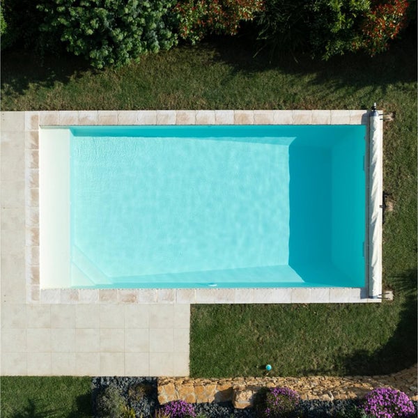 Draufsicht eines rechteckigen Pools im Garten mit Rasenflächen und Bepflanzung