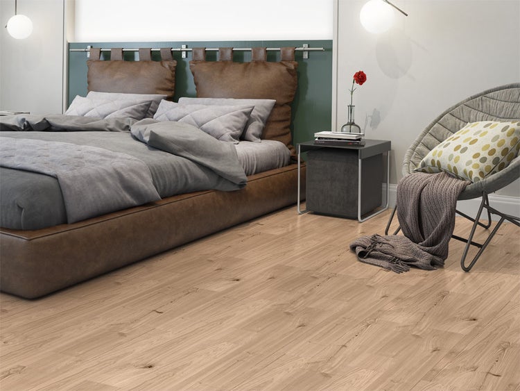 Helles Schlafzimmer mit Laminatboden in Eichenoptik, braunem Lederbett und modernem Sessel.