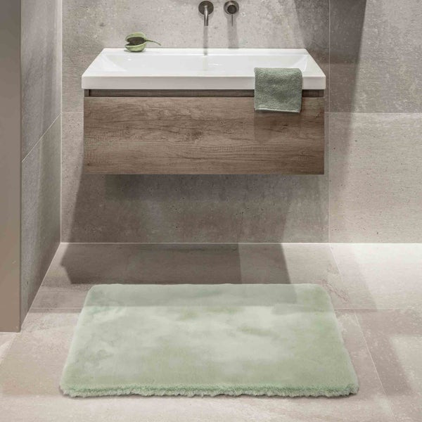 Badezimmer mit Waschtisch, Handtuch und Badteppich.