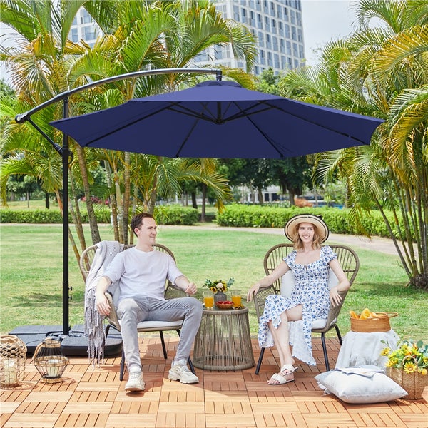 Szene im Freien mit Ampelschirm, Sitzgruppe und Holzfliesen auf einer Terrasse.