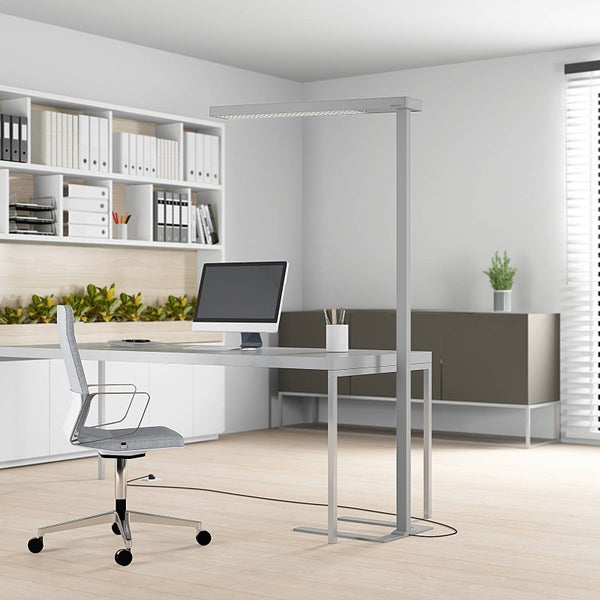 Moderne LED-Stehlampe in einem hellen, organisierten Büro über einem Schreibtisch mit Monitor und ergonomischem Bürostuhl.