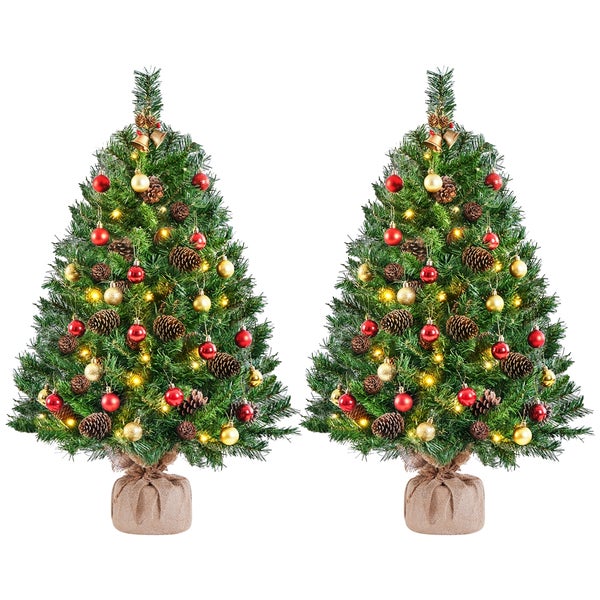 Zwei geschmückte Weihnachtsbäume mit Christbaumkugeln, Tannenzapfen und Beleuchtung