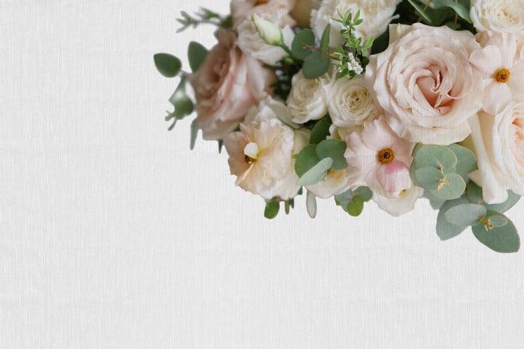 Blumenstrauß aus Rosen Ranunkeln und Eukalyptusblättern auf strukturiertem Untergrund