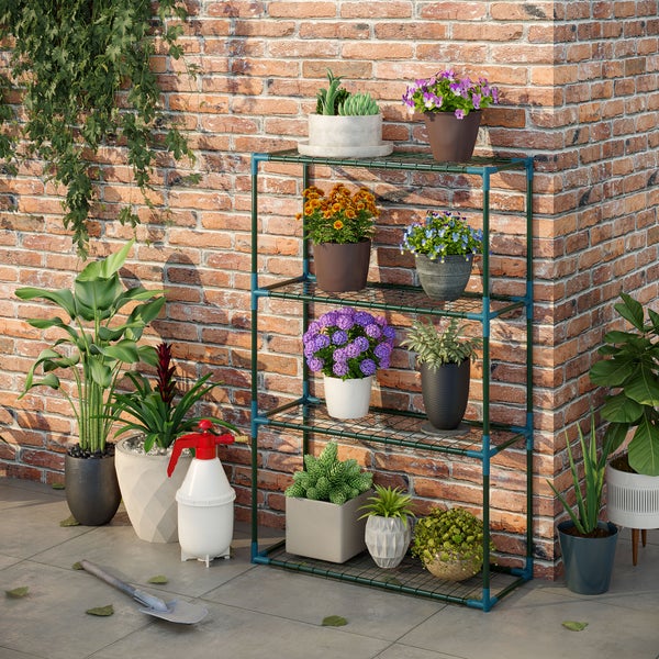 Dunkelgrünes Pflanzenregal aus Metall mit vier Ebenen vor einer Backsteinwand, mit diversen Topfpflanzen, Drucksprüher und Gartenwerkzeug auf Fliesen.
