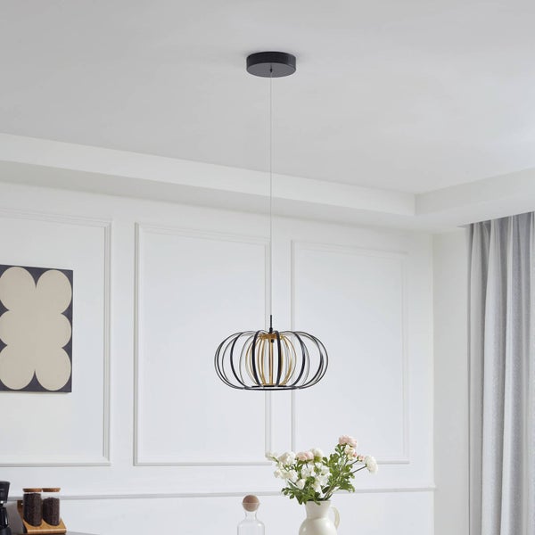 Moderne Pendelleuchte mit einem Schirm aus schwarzen und goldfarbenen Metallstreben in einem hellen Raum mit Wandpaneelen.
