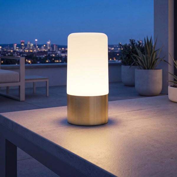 Moderne LED Tischleuchte fuer den Aussenbereich mit zylindrischem Leuchtkörper auf einem metallenen Standfuß auf einer Terrasse