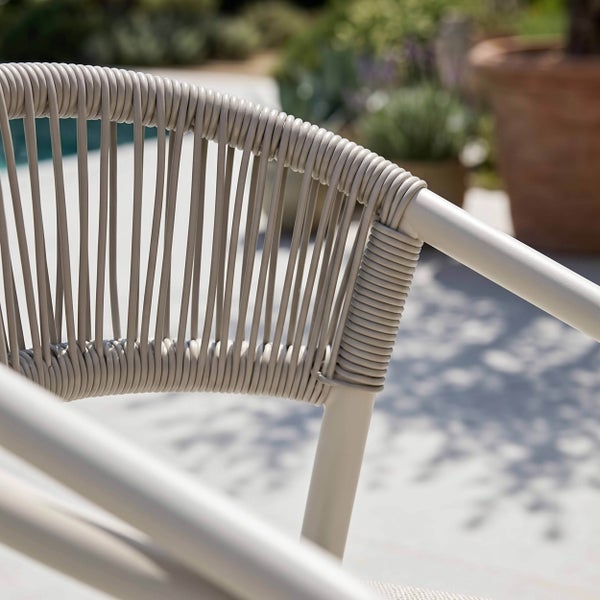 Detailaufnahme eines Gartenstuhls mit Rückenlehne aus Seilgeflecht auf einer Terrasse.